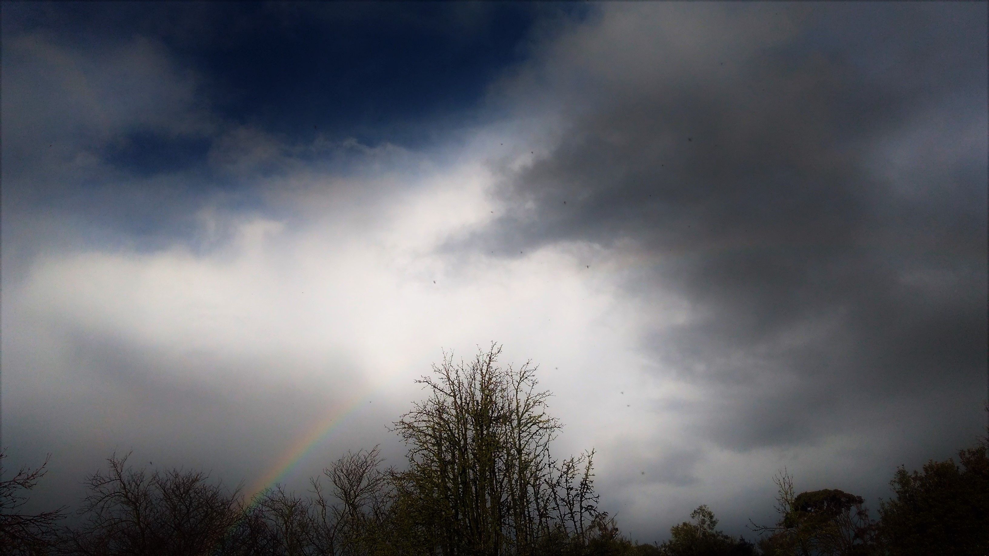 Storm clouds with piece of rainbow coming through